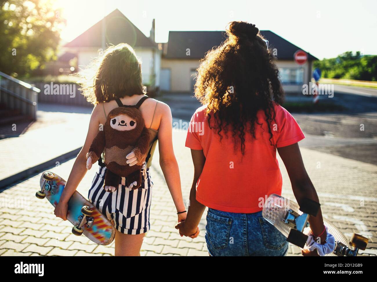 Vista posteriore delle ragazze adolescenti con skateboard all'aperto in città. Foto Stock