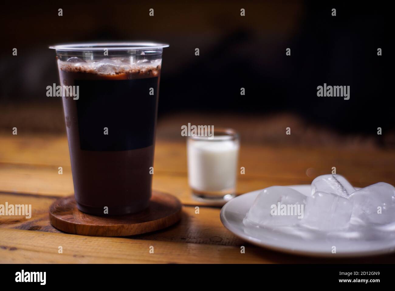 ghiaccio al cioccolato con una miscela di latte e gelatina d'erba a sfondo scuro. bevande fredde con sapore di frutta. mockup di ghiaccio colorato con tazze di plastica Foto Stock