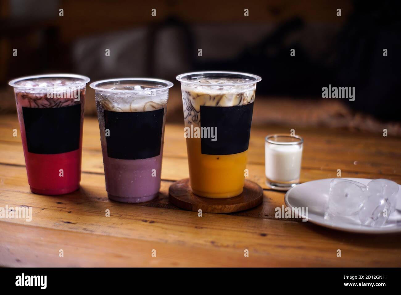 variante di bevande fredde con sapore di frutta. menu di caffè fresco con sfondo scuro. mockup di ghiaccio colorato con tazze di plastica. uva, cioccolato, fragola, Foto Stock