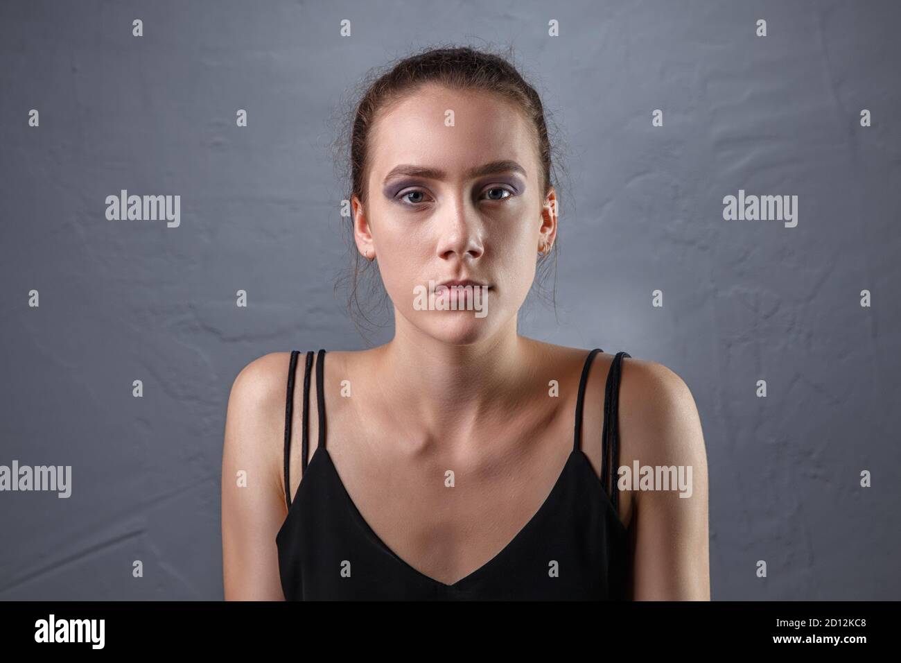 Immagine di giovane donna con trucco incompiuto su sfondo grigio Foto Stock
