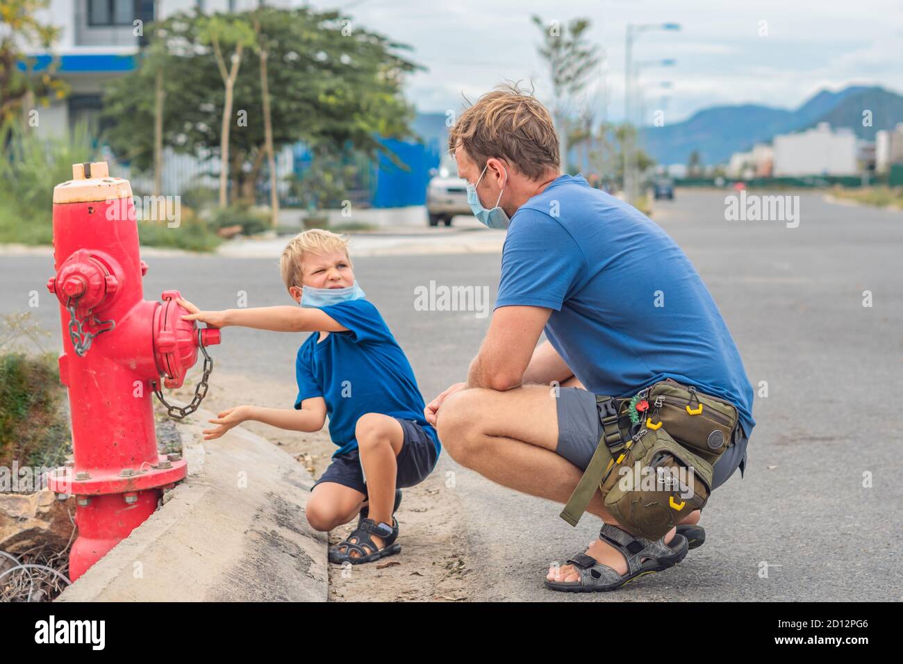 Padre influenza figlio mondview famiglia educazione studiare le abilità di conoscenza quotidiana. Papà in blu maschera COVID spettacolo dire insegnare bambini vigili del fuoco combattenti Foto Stock