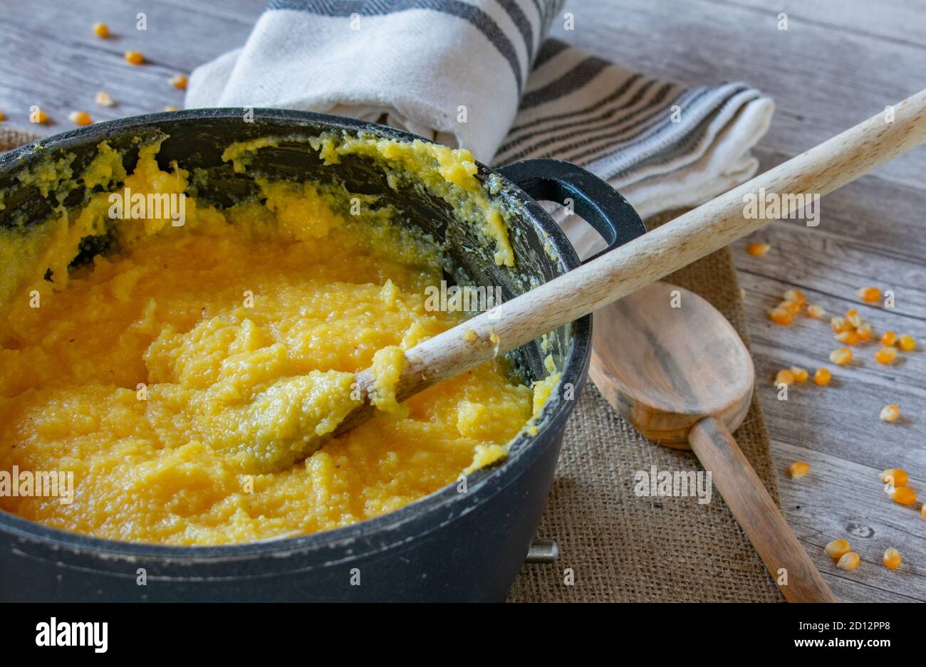 polenta fresca e cremosa in pentola con cucchiaio di legno Foto Stock