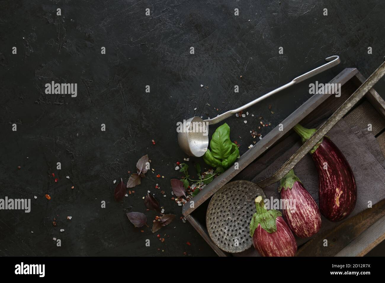 Varietà di melanzane in ciotola nera su fondo di ardesia scuro. Vista dall'alto. Foto Stock