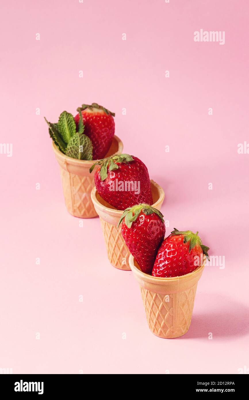Fragole fresche in tazze waffle su rosa pastello pin-up dello sfondo. Copia dello spazio. Foto Stock