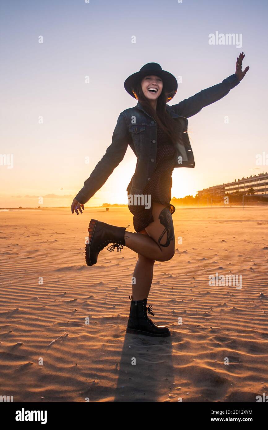 Giovane figura bohémien donna ritratto su una passeggiata al tramonto sulla spiaggia. Vista orizzontale. Scatto medio. Foto Stock