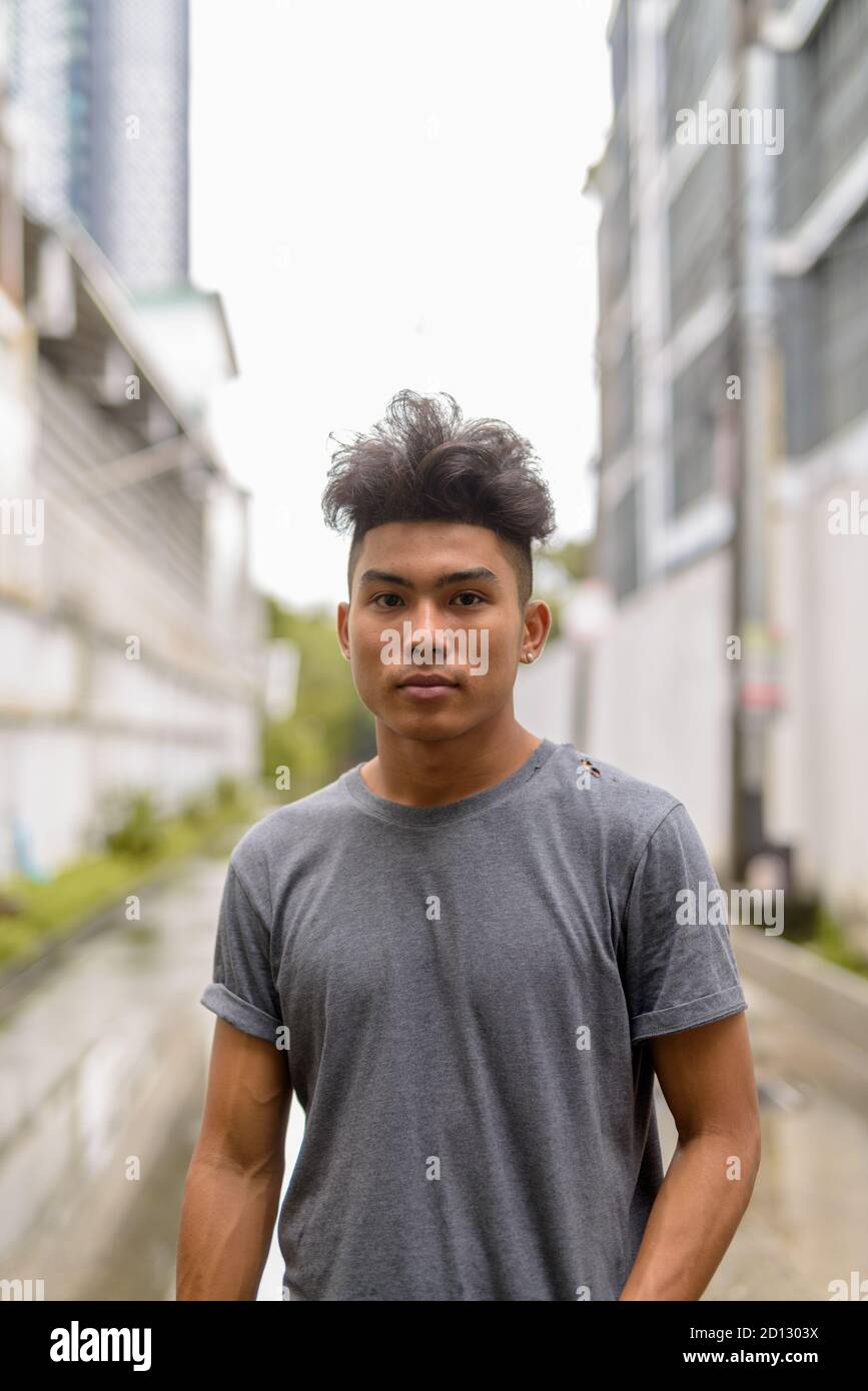 Giovane asiatico con capelli ricci nelle strade all'aperto Foto Stock