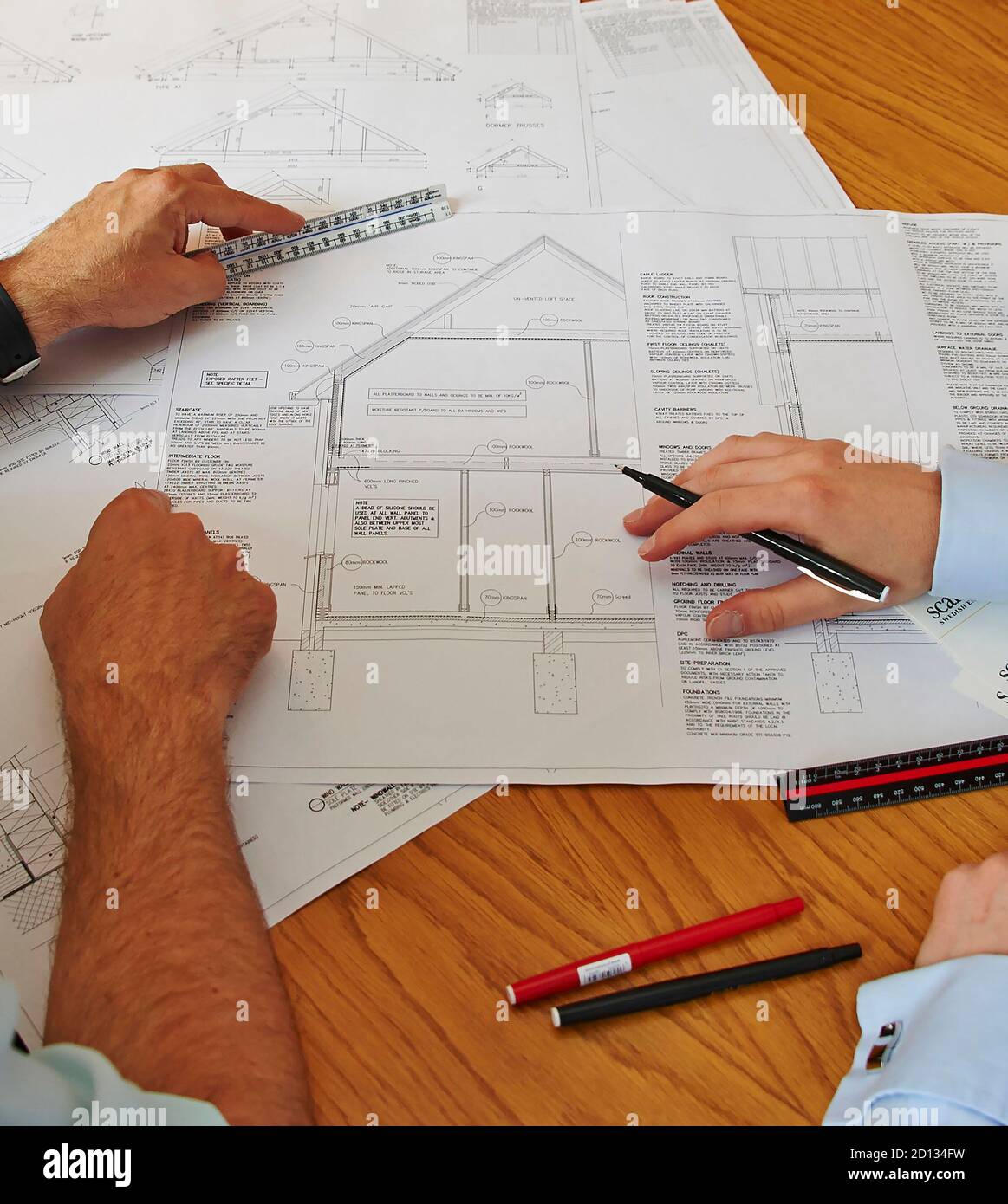 Industria edile del Regno Unito al lavoro - riunione del sito guardando piani Foto Stock