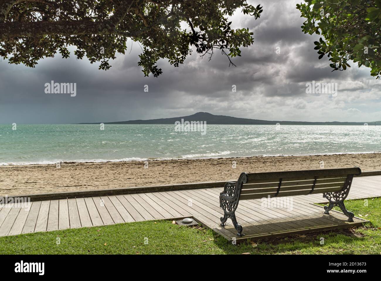 Nuvole doccia sul vulcano Rangitoto attraverso la spiaggia di St Helier ad Auckland, Nuova Zelanda Foto Stock