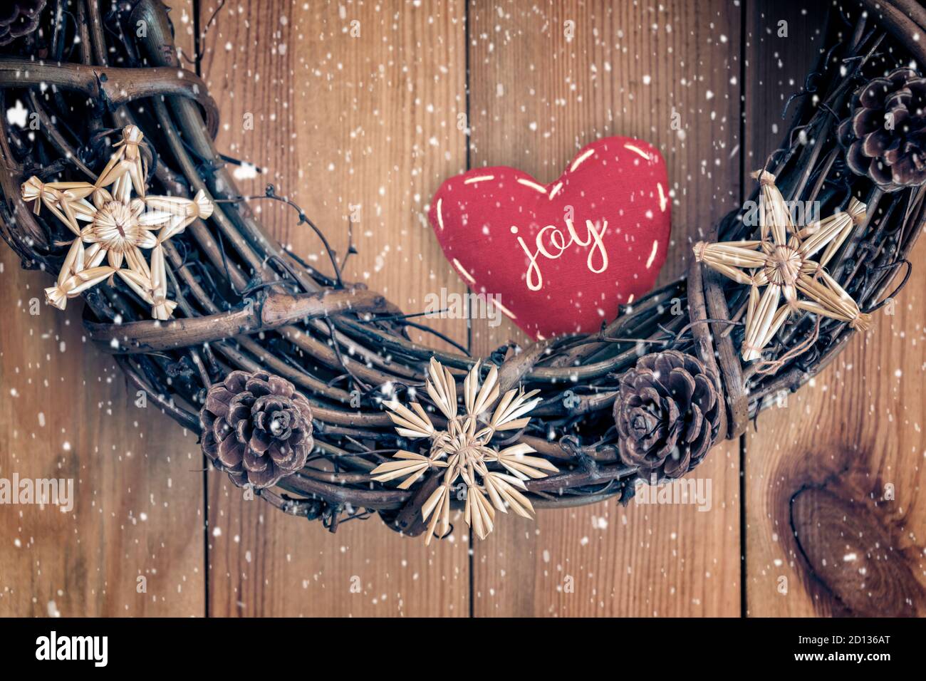 Gioia carta di Natale. Corona di Natale rustica, ricamo di gioia, neve d'inverno e tavole di legno sfondo Foto Stock