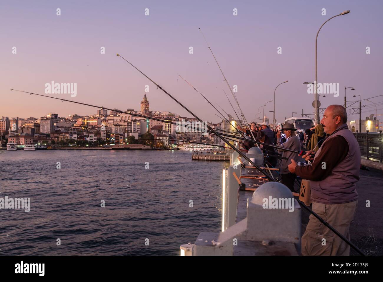Pescatore turco non identificato sul ponte di Galata con la torre di Galata sullo sfondo a Istanbul Foto Stock