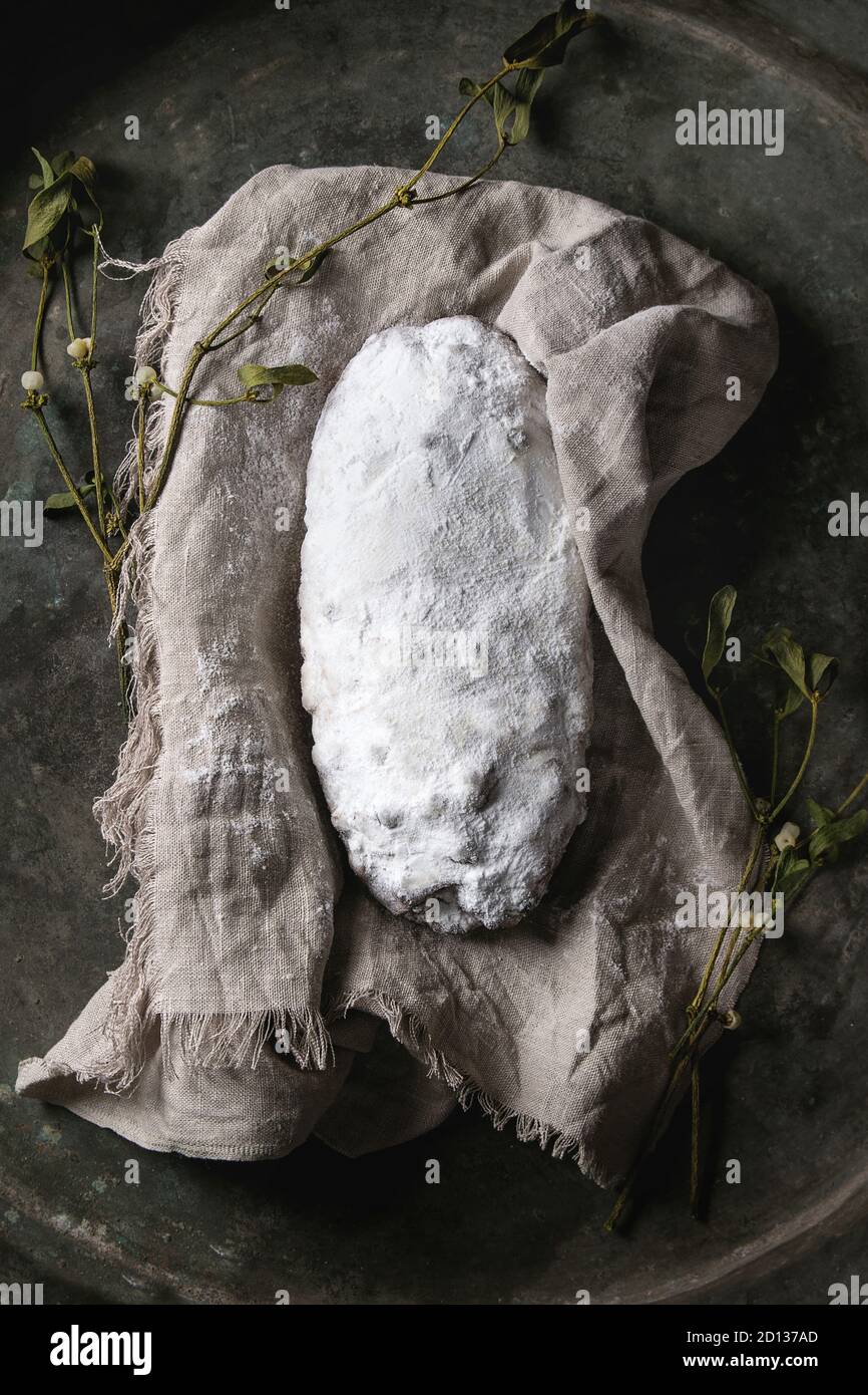 Tutta la torta di Natale, tradizionale festa tedesca la cottura. Lo Stollen integrali con uvetta e zucchero in polvere sul tovagliolo di lino con rami di vischio o Foto Stock