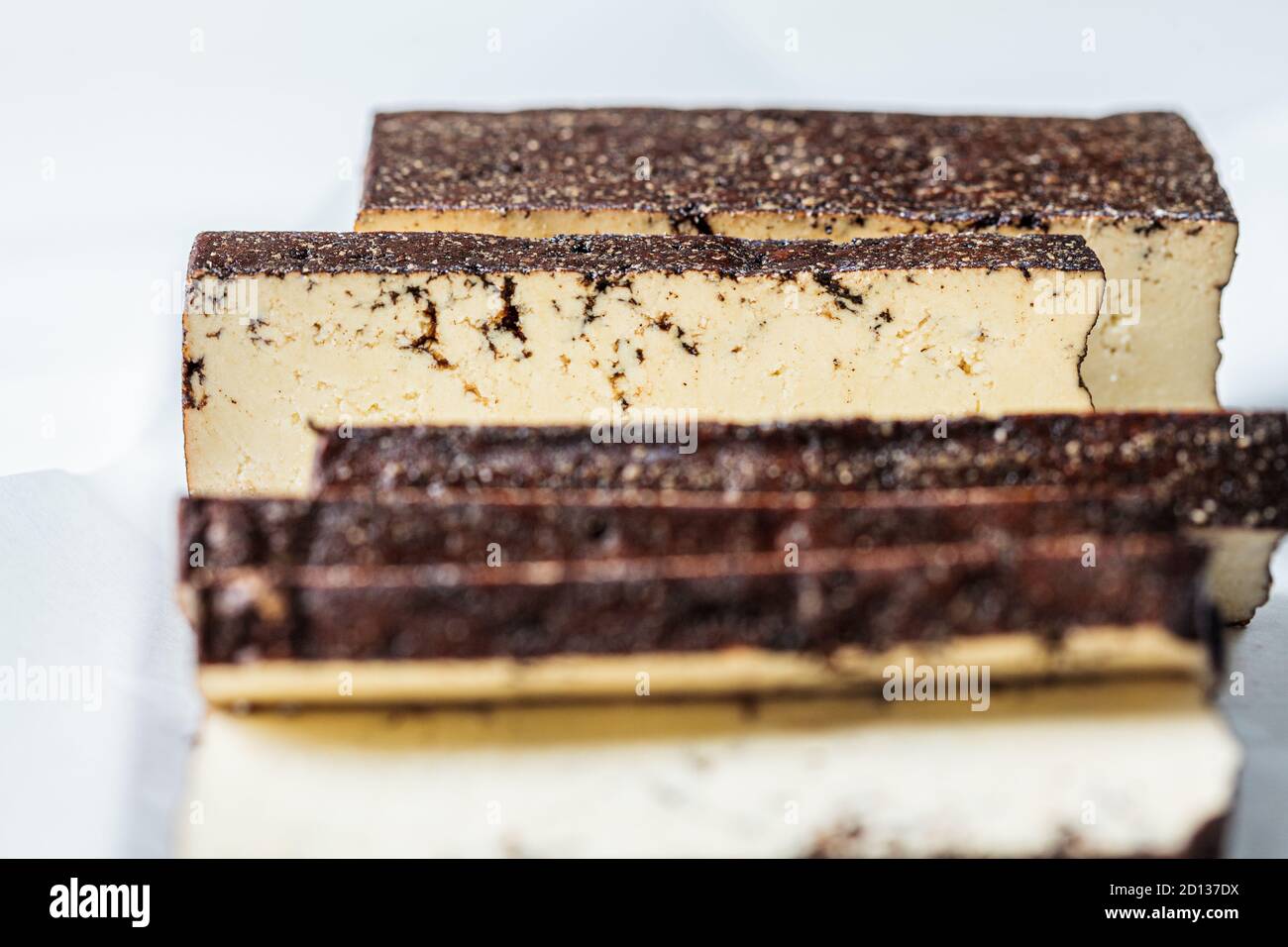 Tofu affumicato a fette su una tavola bianca, sfondo bianco. Concetto di cibo vegano. Foto Stock