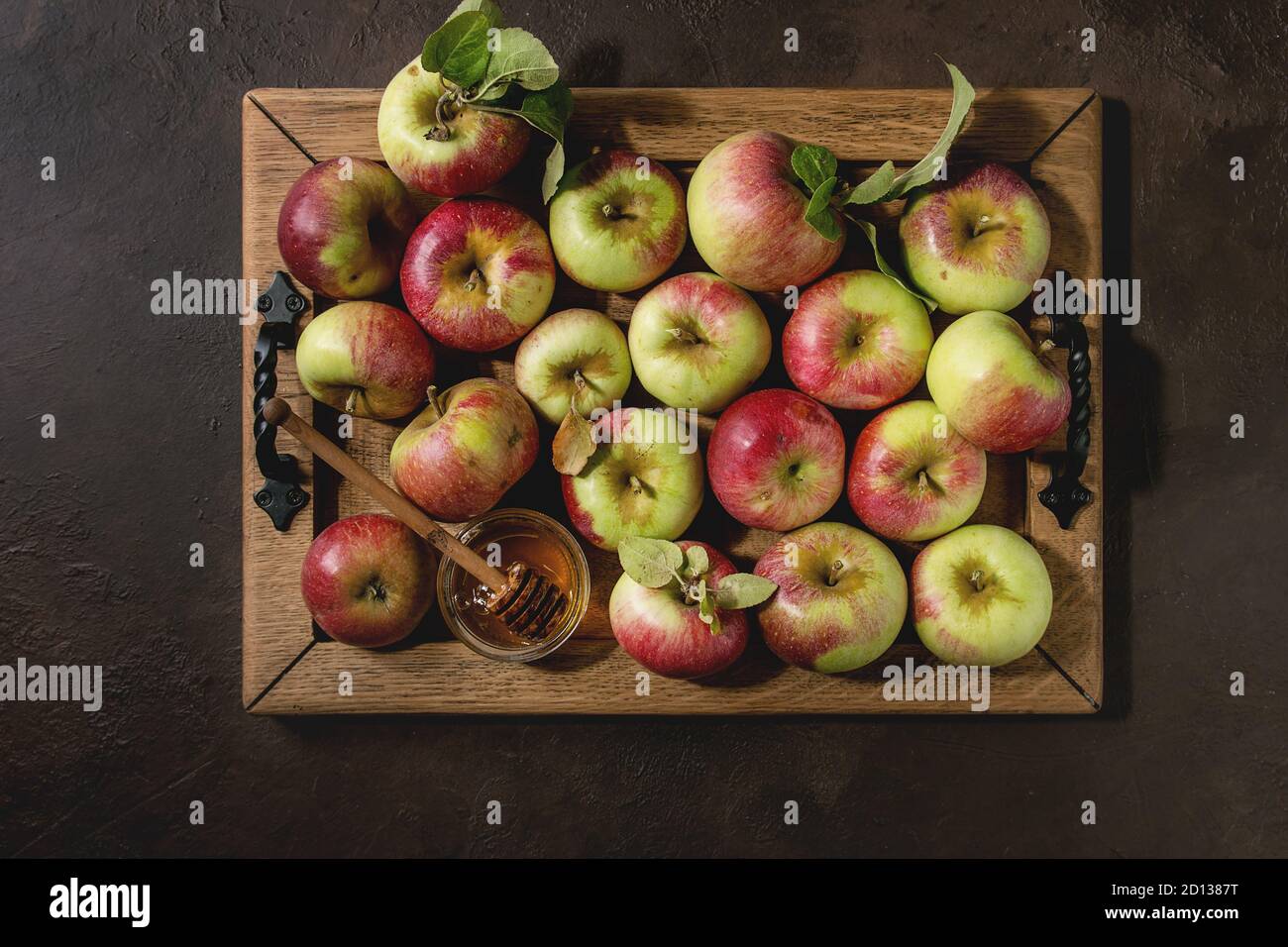 Mature Giardinaggio organico verde rosso di mele con foglie e di un vasetto di miele sul vassoio in legno scuro su sfondo di texture. Appartamento laico, spazio. Raccolto autunnale. Foto Stock