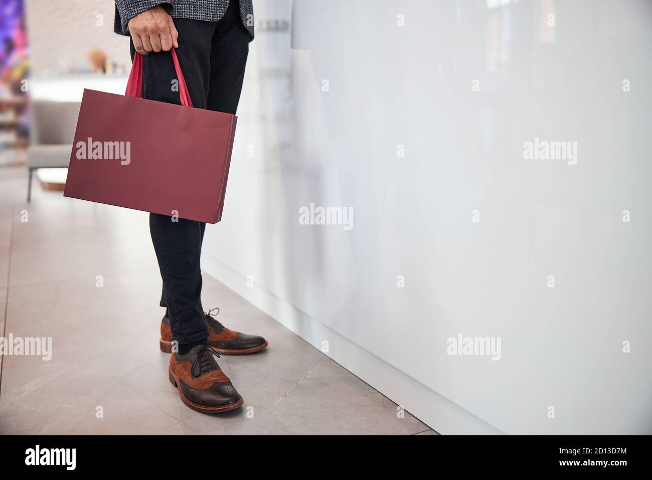 Uomo alto ed elegante con una borsa regalo di marca Foto Stock