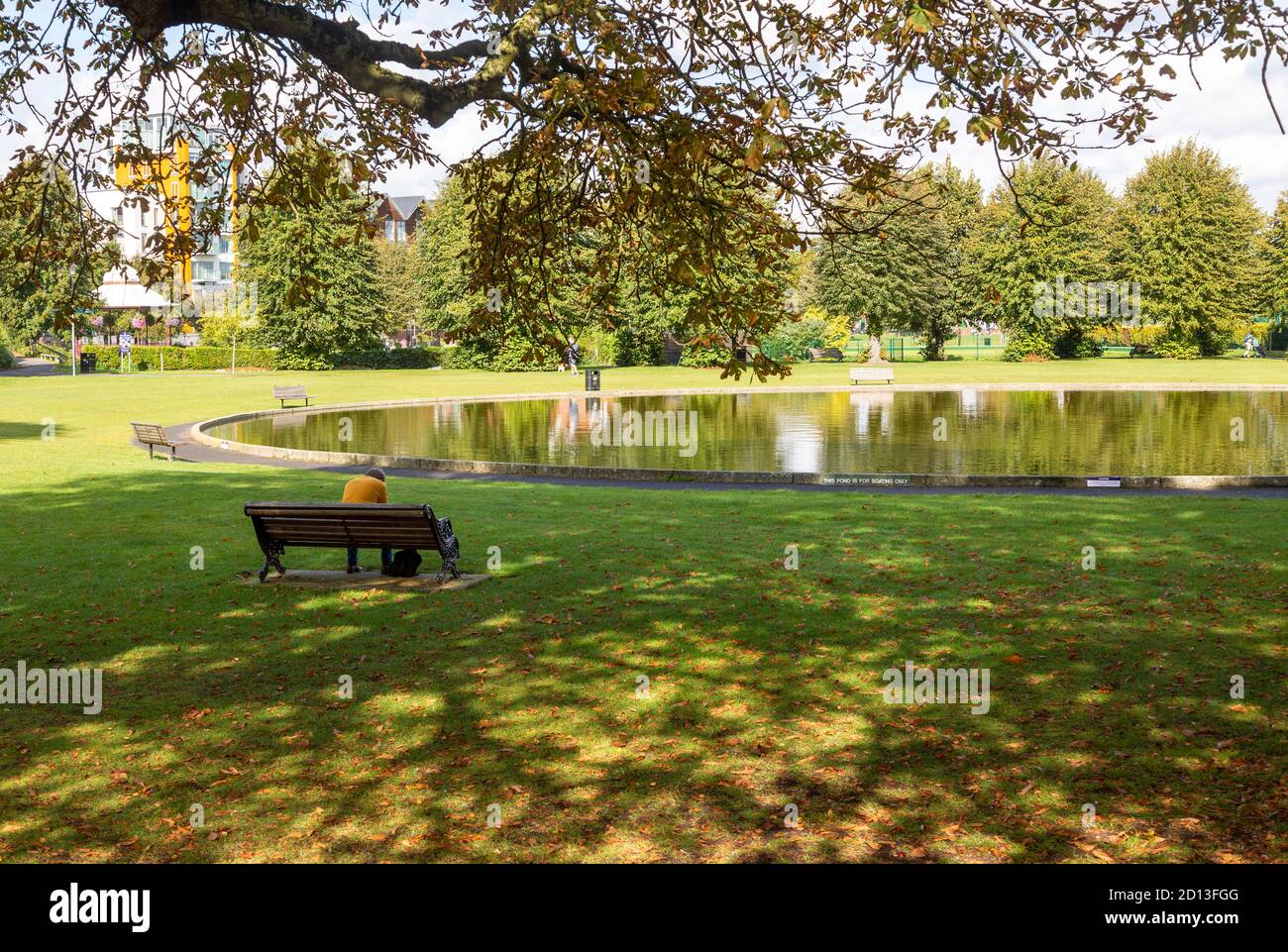 Canottaggio stagno lago in Victoria Park, Newbury, Berkshire, Inghilterra, UK persona seduta su panca da solo Foto Stock