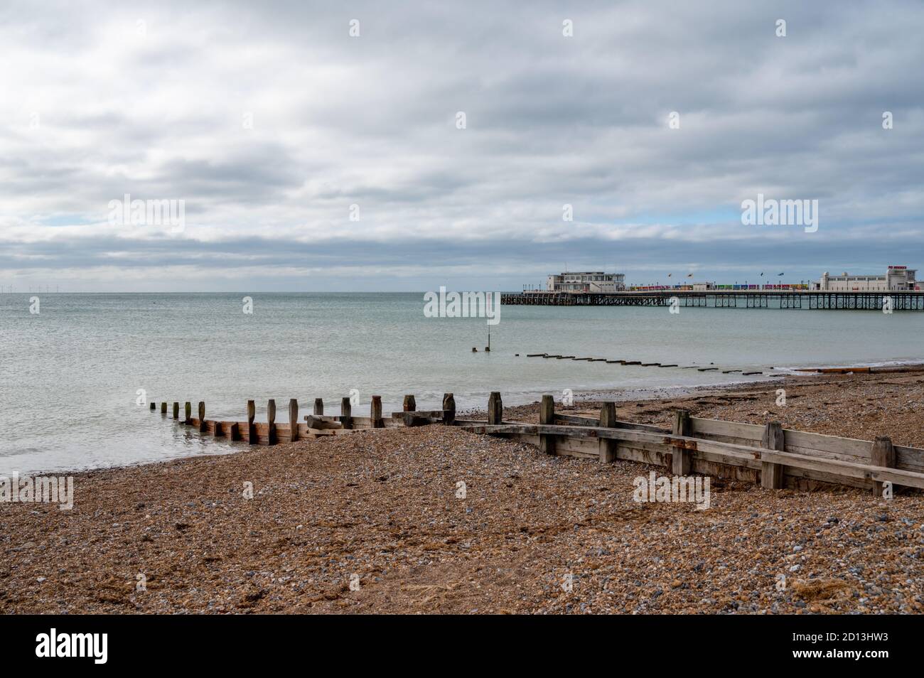Guardando ad ovest al molo di Worthing sulla spiaggia con groynes di legno distanziati per proteggere contro l'erosione del mare. West Sussex, Regno Unito. Foto Stock