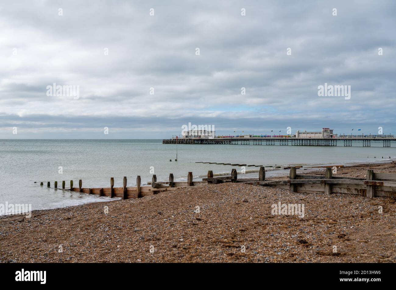 Guardando ad ovest al molo di Worthing sulla spiaggia con groynes di legno distanziati per proteggere contro l'erosione del mare. West Sussex, Regno Unito. Foto Stock
