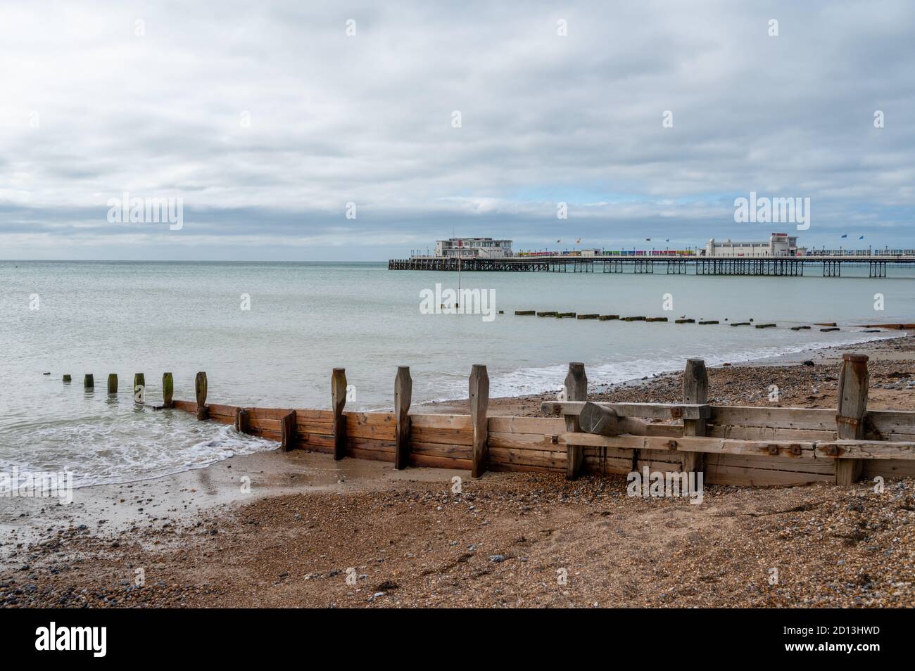 Guardando ad ovest al molo di Worthing sulla spiaggia con groynes di legno distanziati per proteggere contro l'erosione del mare. West Sussex, Regno Unito. Foto Stock