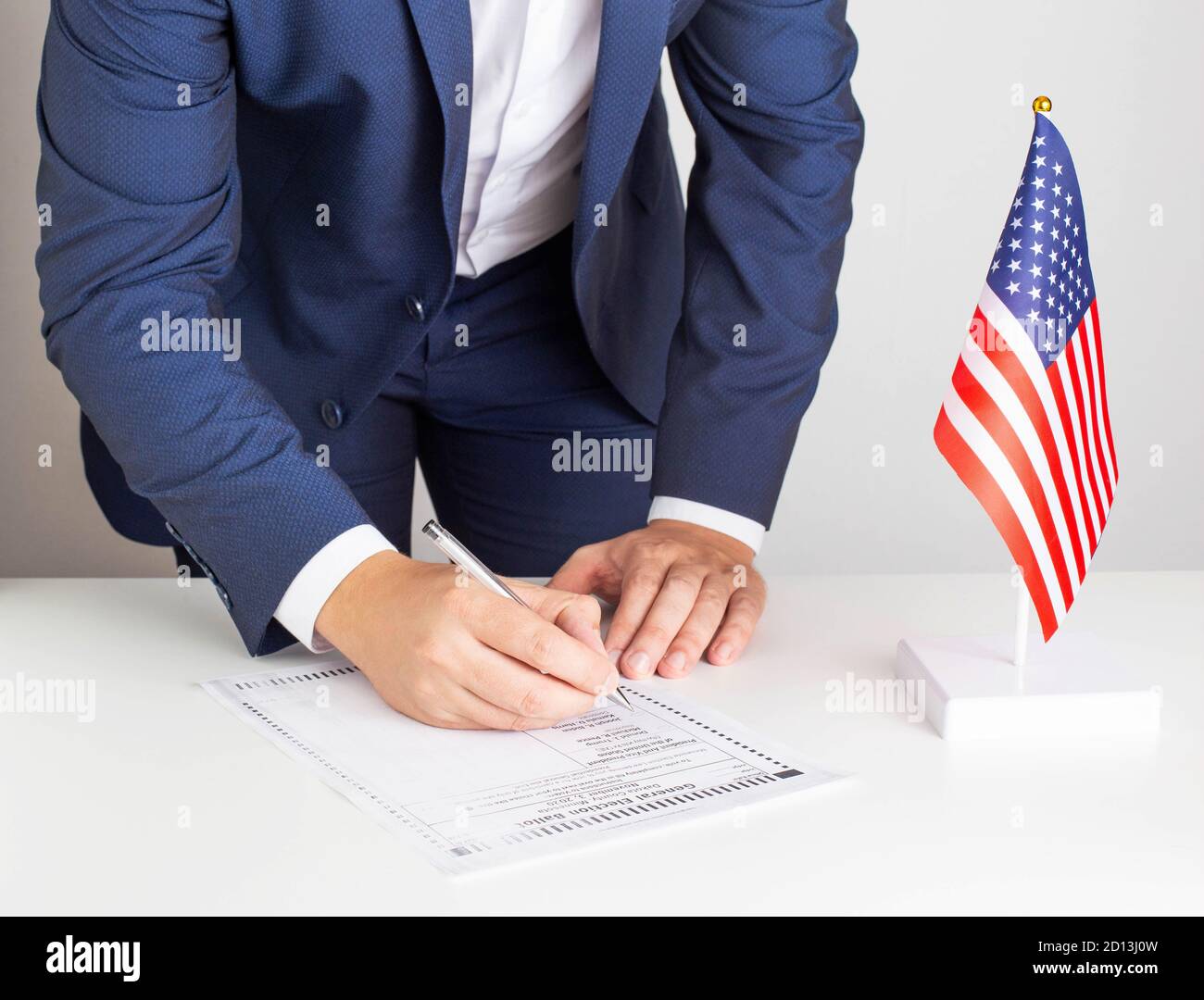 Una bandiera degli Stati Uniti è sul tavolo. Una persona in tuta fa una scelta tra i candidati per il presidente nel 2020 o 2024. Il voto ufficiale generale Foto Stock