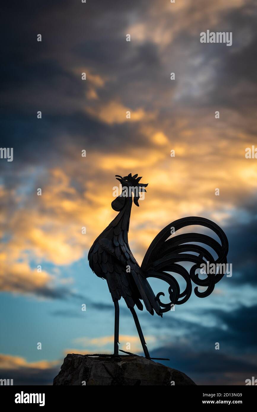 Una silhouette di gallo nero, simbolo del vino Chianti, si distingue da un cielo tempestoso al tramonto nel villaggio di Vertine, in Toscana Foto Stock