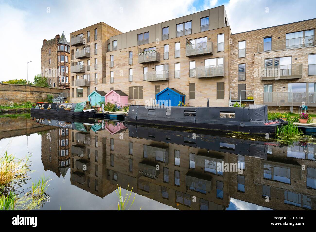 Moderni blocchi di appartamenti e barche strette ormeggiate lungo il canale Union a Fountainbridge a Edimburgo, Scozia, Regno Unito Foto Stock