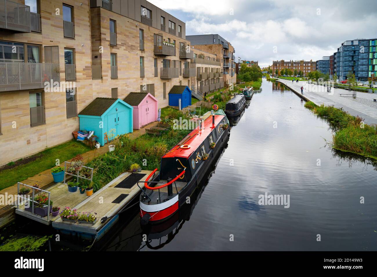 Moderni blocchi di appartamenti e barche strette ormeggiate lungo il canale Union a Fountainbridge a Edimburgo, Scozia, Regno Unito Foto Stock