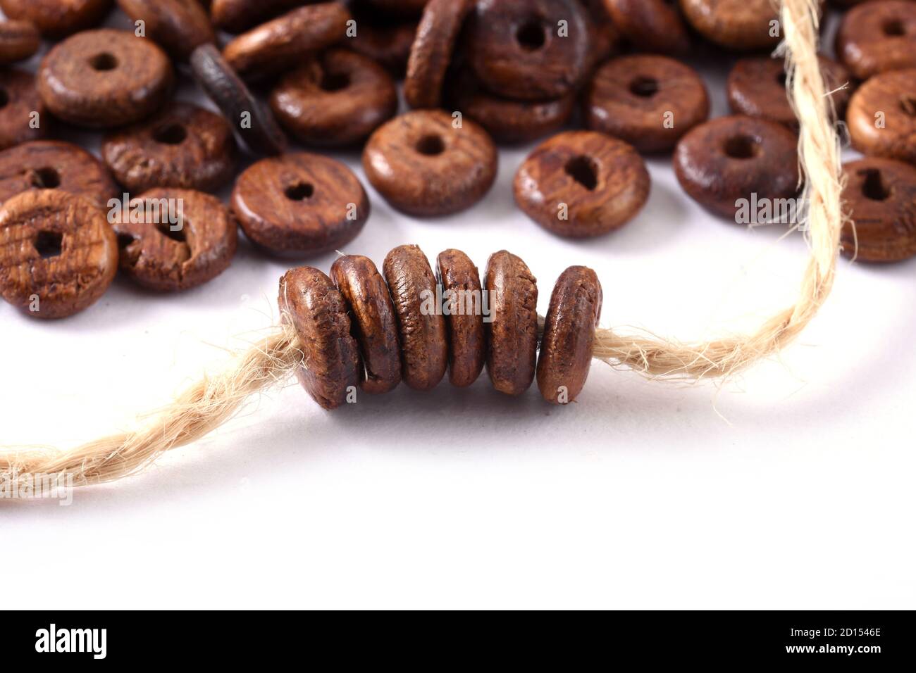 Perline di legno con corda di iuta naturale spago su sfondo bianco. Primo piano, macro. Foto Stock