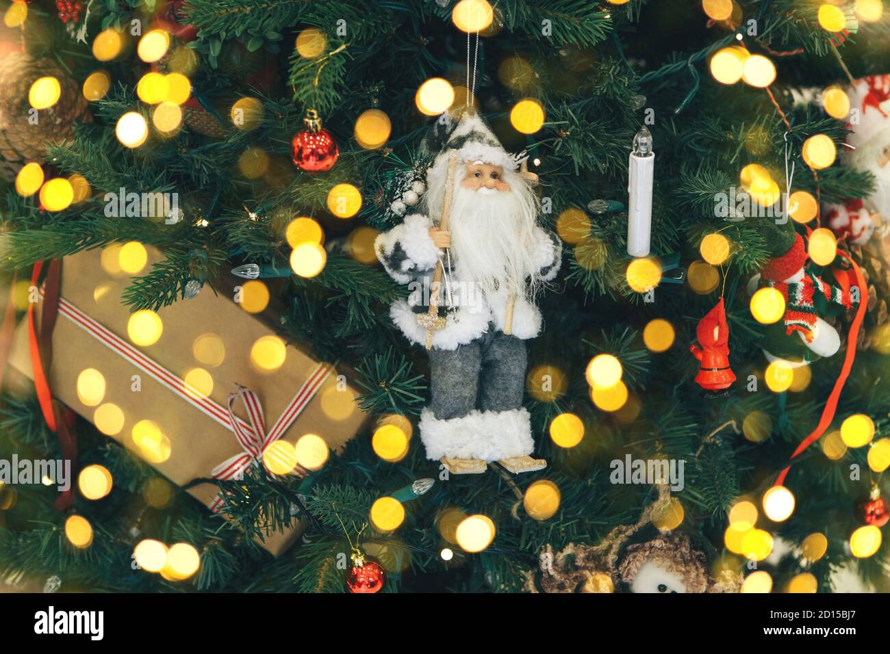 Primo piano del giocattolo di Natale di Babbo Natale sull'albero di Natale. Ci sono luci intorno. Foto Stock