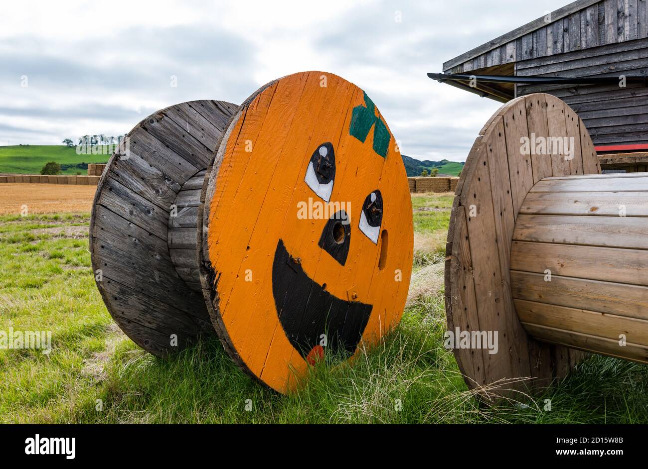 La faccia della zucca felice di Halloween è dipinta sulla ruota del cavo o sul tamburo in patch field, East Lothian, Scozia, Regno Unito Foto Stock