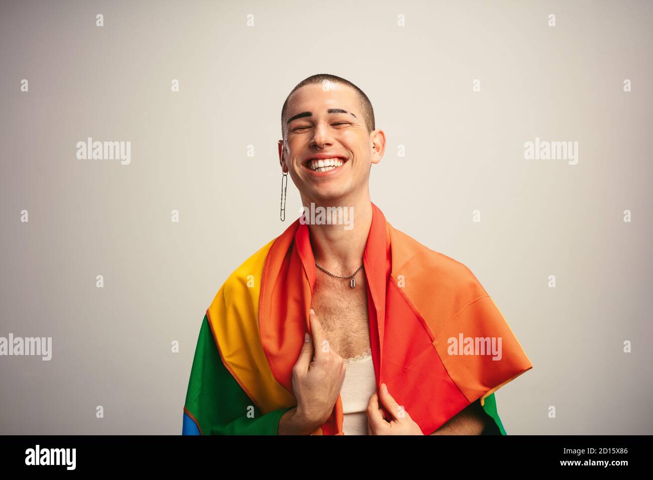 Allegro uomo transgender con bandiera gay orgoglio. Genere fluido maschio con bandiera lgbt su sfondo bianco. Foto Stock