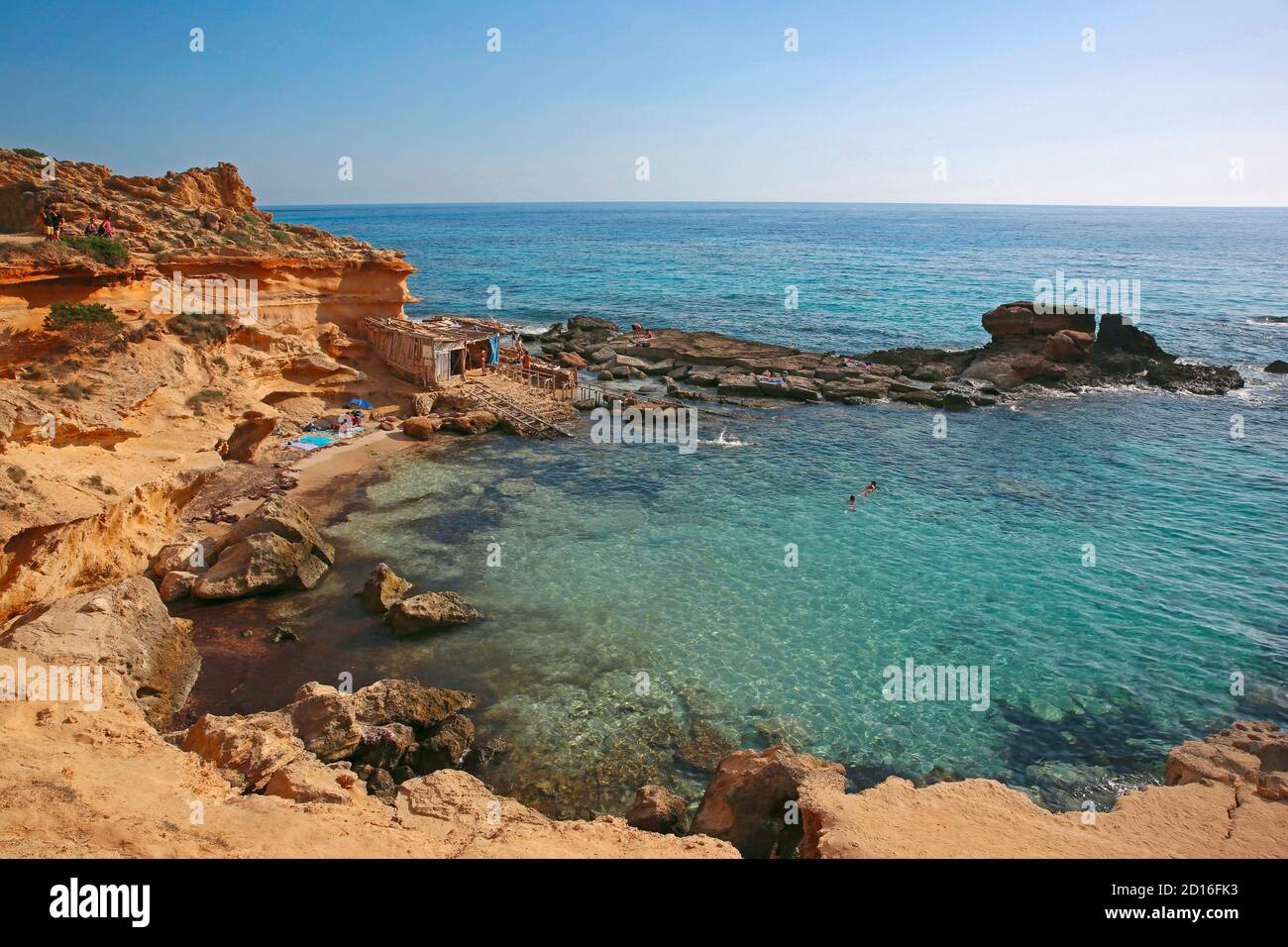Spagna, Isole Baleari, formentera, calo des mort, visitatori estivi adagiati su una baia fiancheggiata da scogliere rosse e rocce in un forte di acque turchesi Foto Stock