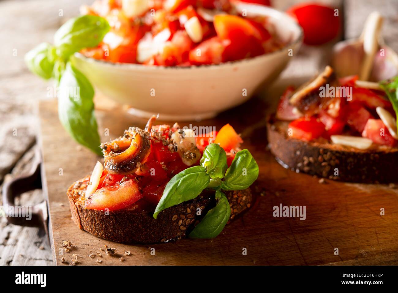 Gustosi antipasti italiani salati bruschetta, fette di pane guarnito di pomodoro basilico, primo piano su una tavola di legno Foto Stock