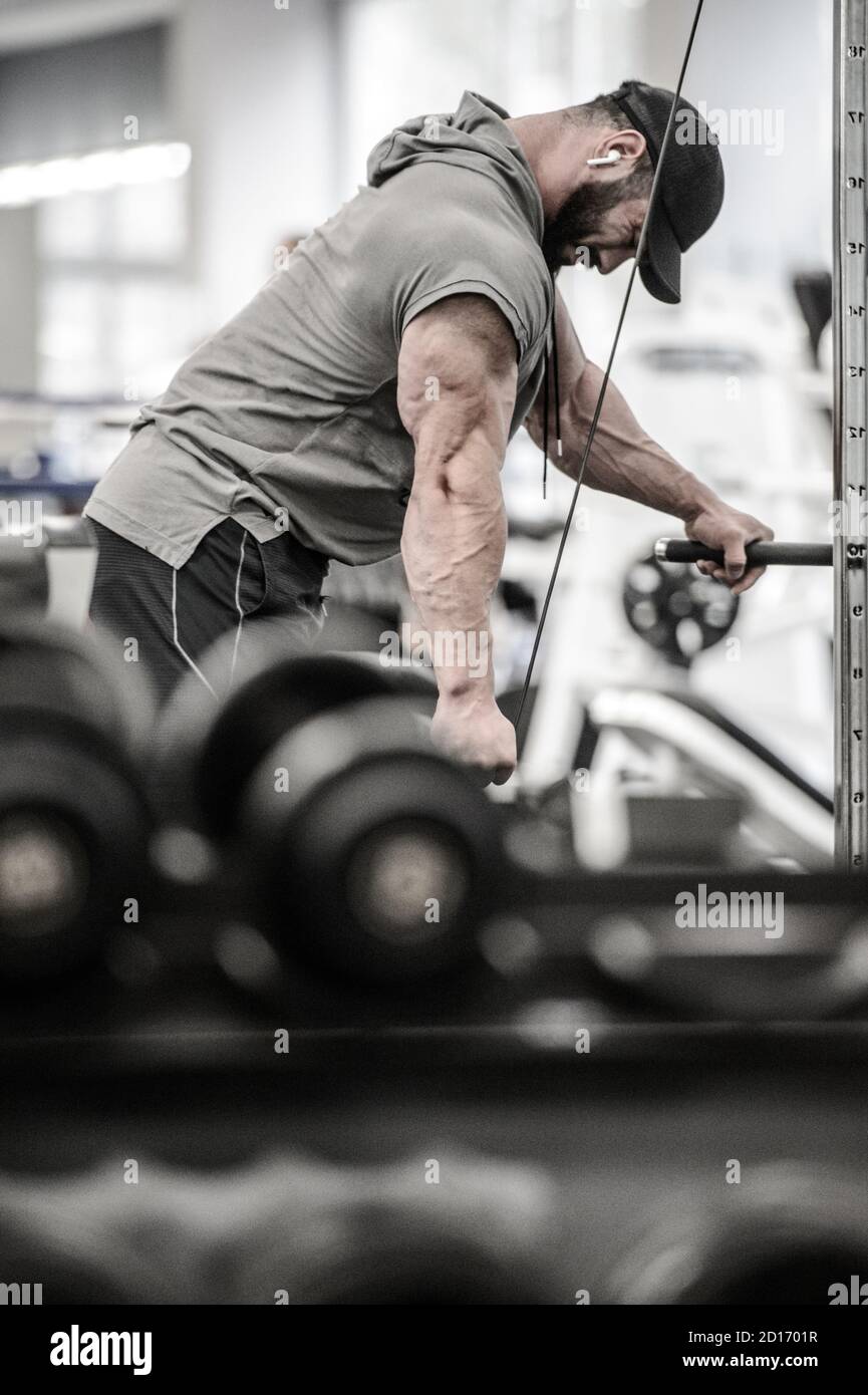 uomo giovane e forte bearded in cappello e senza maniche felpa con  cappuccio pesante allenamento in palestra sport utilizzando l'attrezzatura  fitness per l'ascolto di musica su wireless Foto stock - Alamy