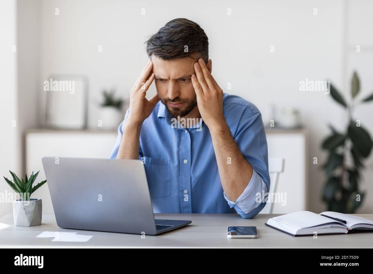 Mancanza di ispirazione. Un uomo d'affari attento e attento si è concentrato sullo schermo del notebook in ufficio Foto Stock