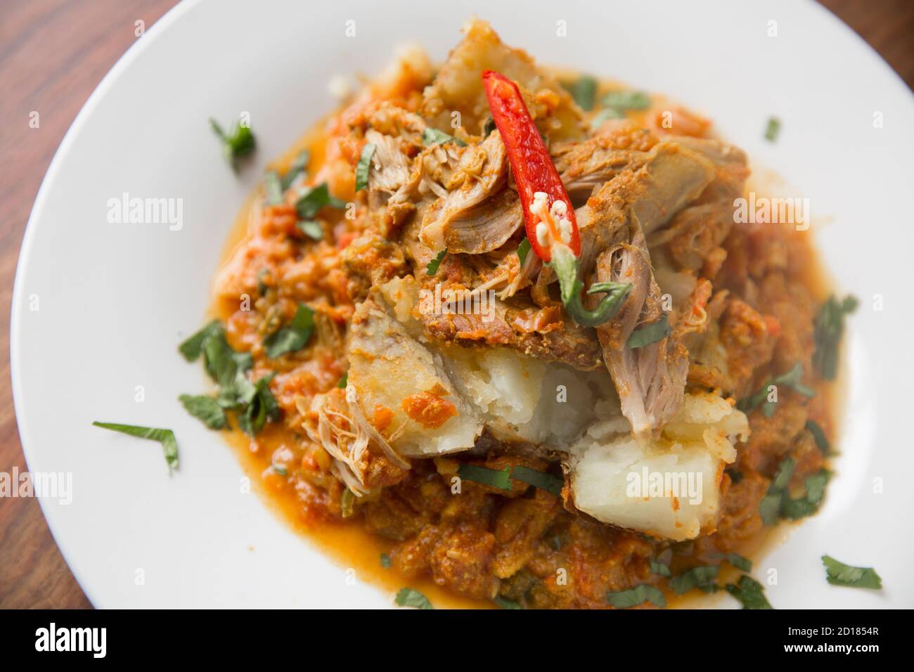 Curry di cervo servito su una patata di giacca e guarnito con un peperoncino rosso. Dorset Inghilterra Regno Unito GB. Foto Stock