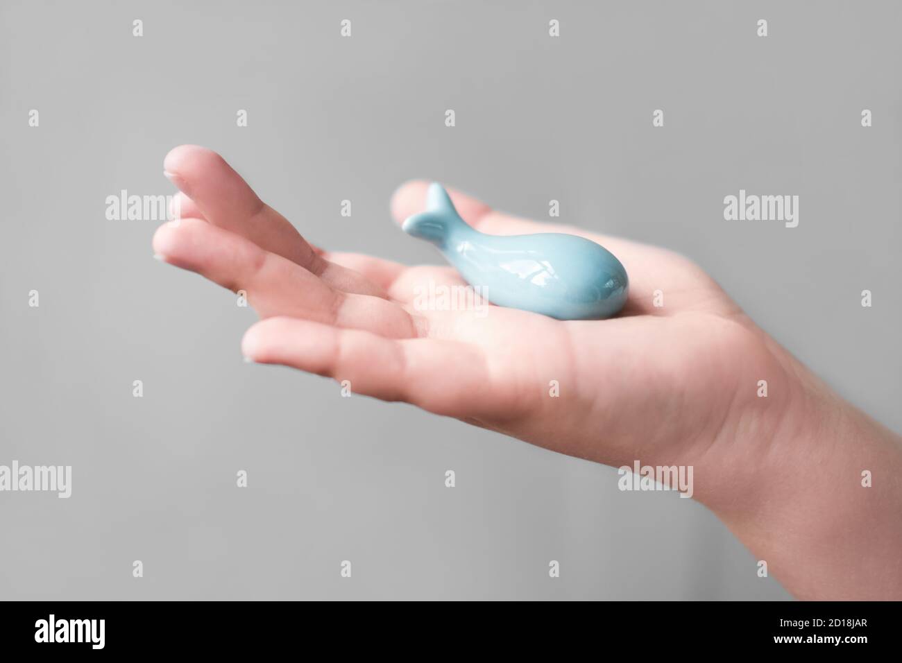 la balena blu è tenuta a mano dell'uomo. salva le balene e proteggi la natura. concetto eco-attivismo. balena blu in ceramica nelle mani degli adolescenti. sensibile all'inquinamento dell'oceano. Foto Stock