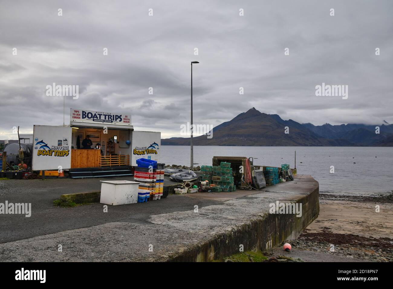 Porto di Elgol, Isola di Skye, Scozia con chiosco per gite in barca, muro del porto, spiaggia sabbiosa e montagne sullo sfondo Foto Stock