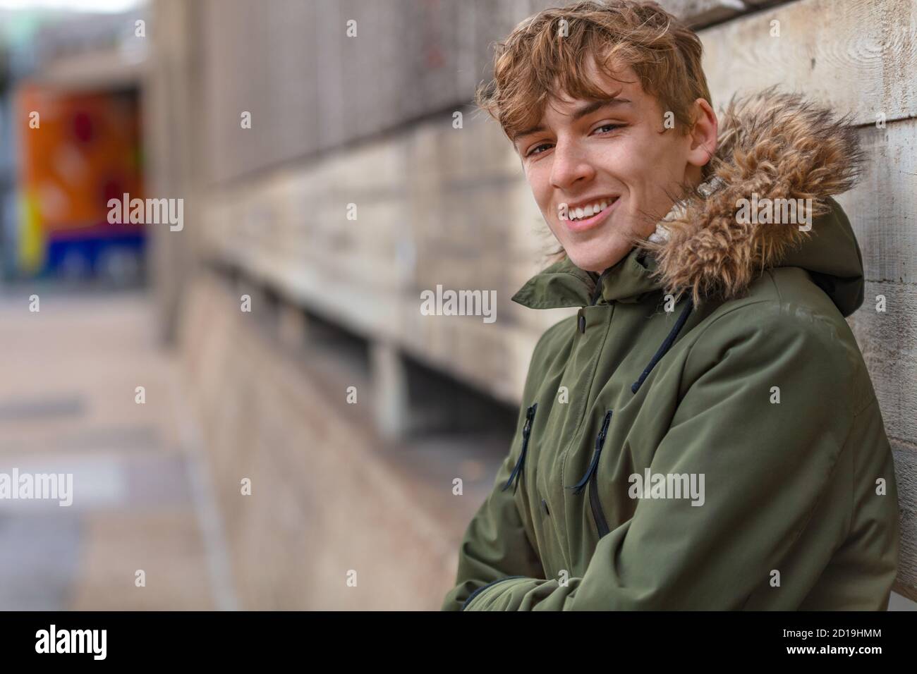 Maschio adolescente adulto giovane che indossa una giacca di parka fuori e. sorridente Foto Stock
