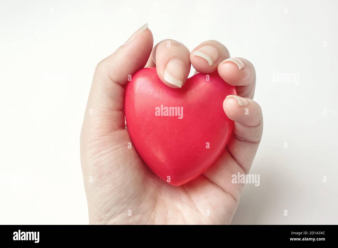 La mano della donna tiene il cuore rosso sullo sfondo bianco. Assicurazione sanitaria, donazione, concetto di salvataggio della vita Foto Stock