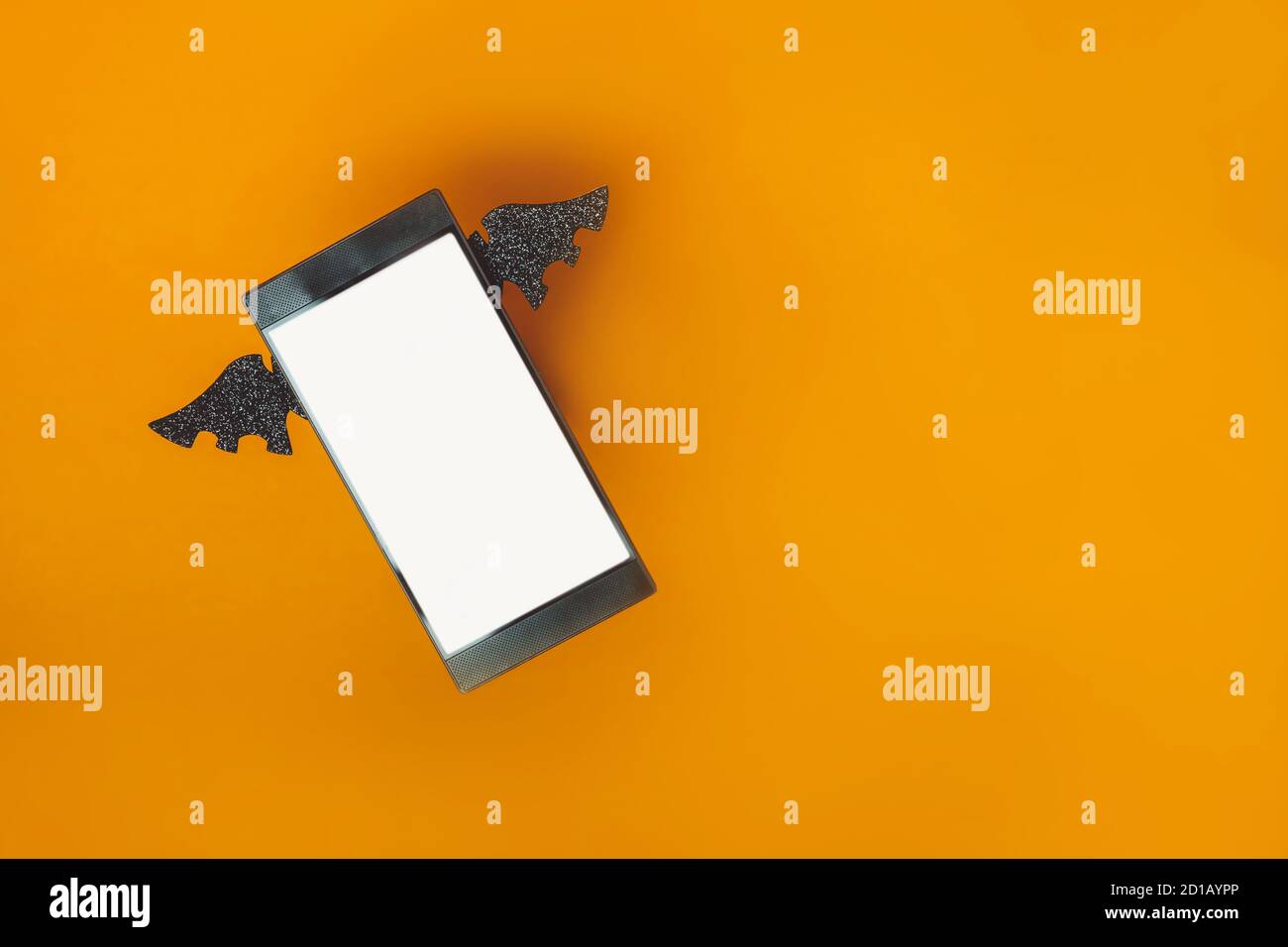 Primo piano smartphone con schermo bianco vuoto decorato con ali a forma di pipistrello sullo sfondo arancione. Saluti, applicazione o g di Halloween Foto Stock