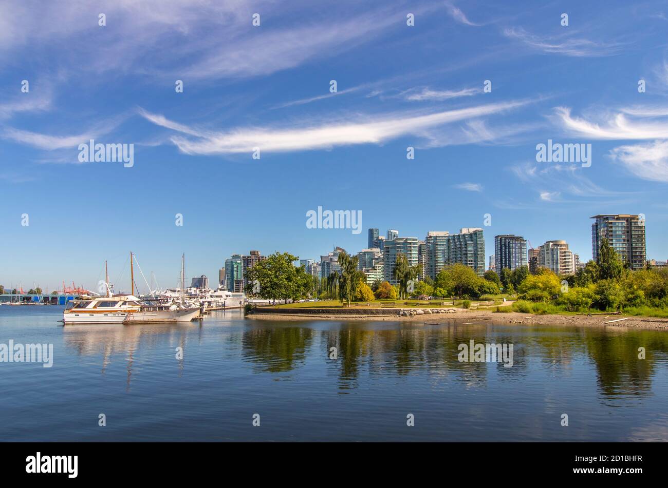 Il lungomare di Vancouver, British Columbia. La vista sui grattacieli del centro e gli yacht / le barche a vela attraccate da Stanley Park. Cielo blu con nuvole streaky. Foto Stock