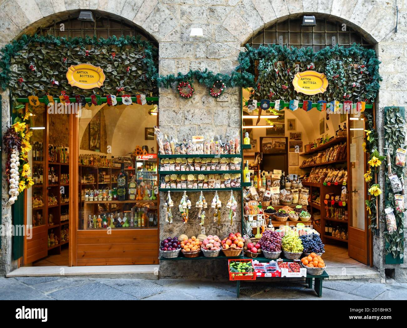 L'esterno di un negozio di alimentari nel centro storico con frutta fresca e verdure esposte sul marciapiede, Siena, Toscana, Italia Foto Stock