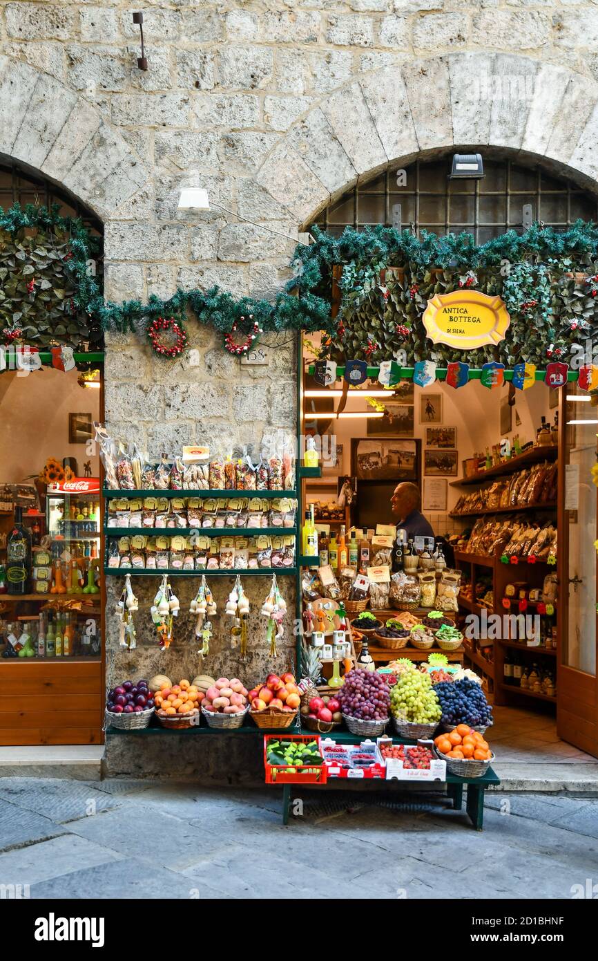 L'esterno di un negozio di alimentari nel centro storico con frutta fresca e verdure esposte sul marciapiede, Siena, Toscana, Italia Foto Stock