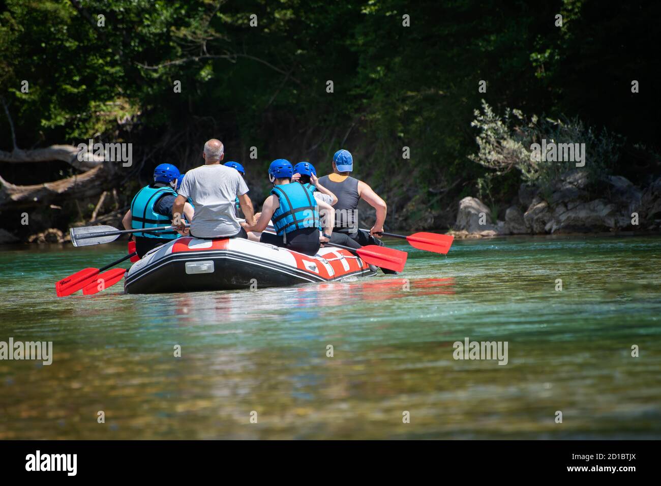 La squadra di rafting scende lungo il fiume nella bella giornata di sole. Vista posteriore. Foto Stock