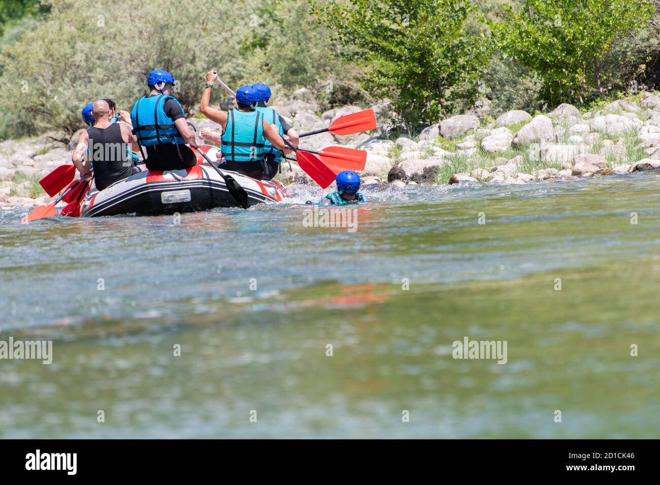 La squadra di rafting scende lungo il fiume nella bella giornata di sole. Vista posteriore. Foto Stock