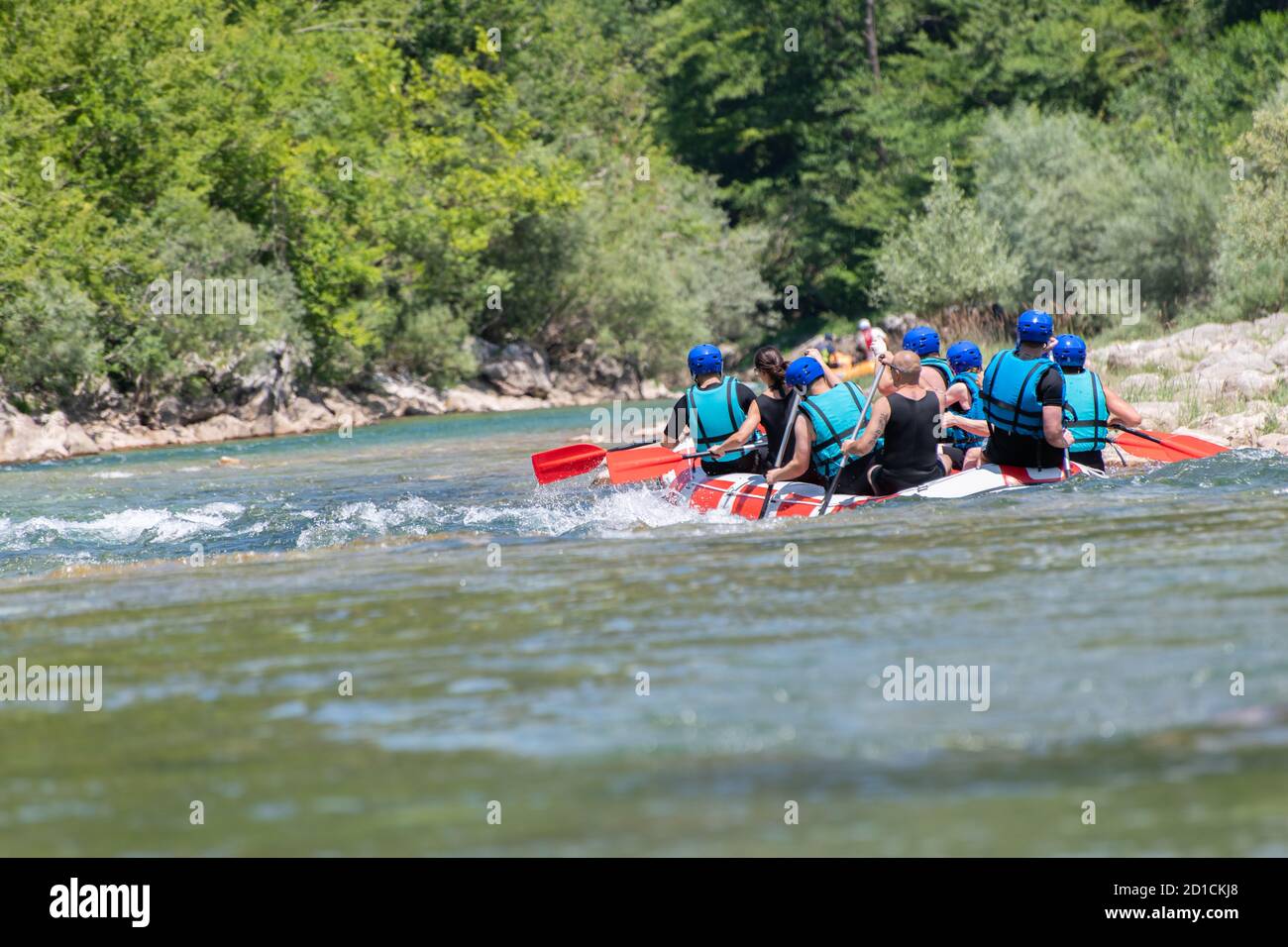 La squadra di rafting scende lungo il fiume nella bella giornata di sole. Vista posteriore. Foto Stock