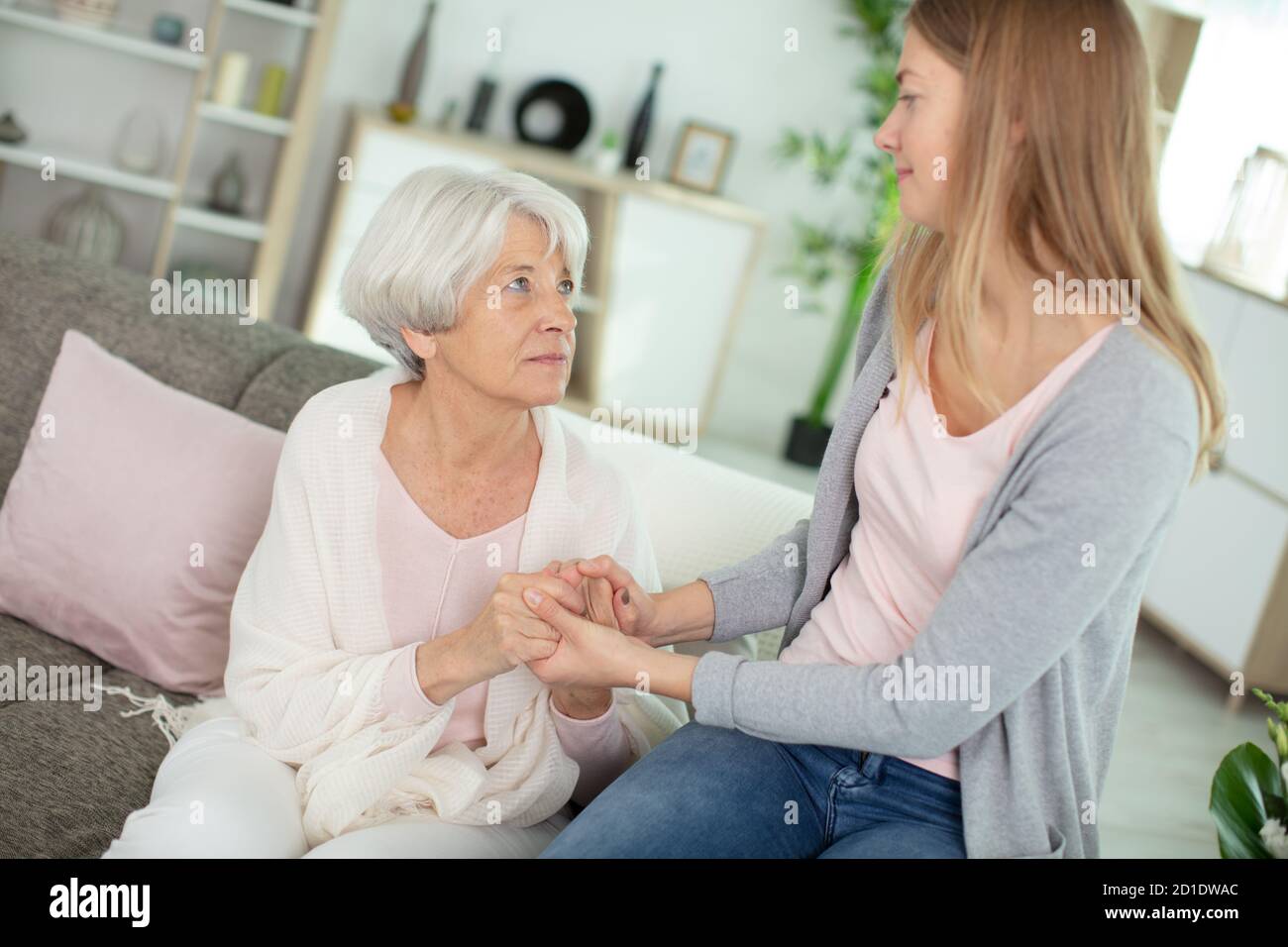 bella anziana e sua figlia sorridente mentre si siede sul divano Foto Stock
