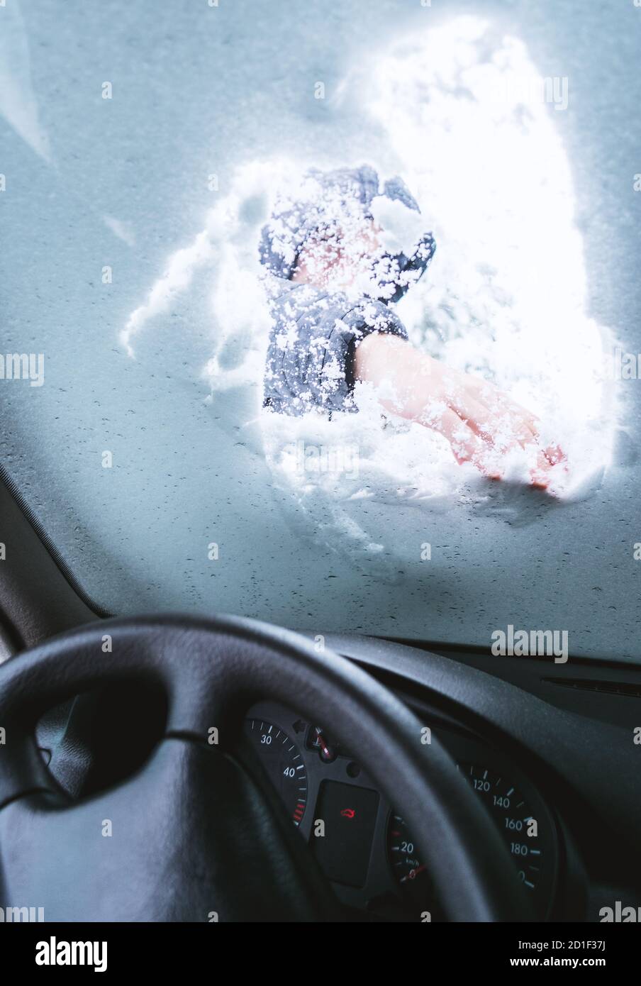Uomo all'aperto che pulisce la neve sulla sua auto parabrezza.Vista dall'interno dell'auto. Foto Stock
