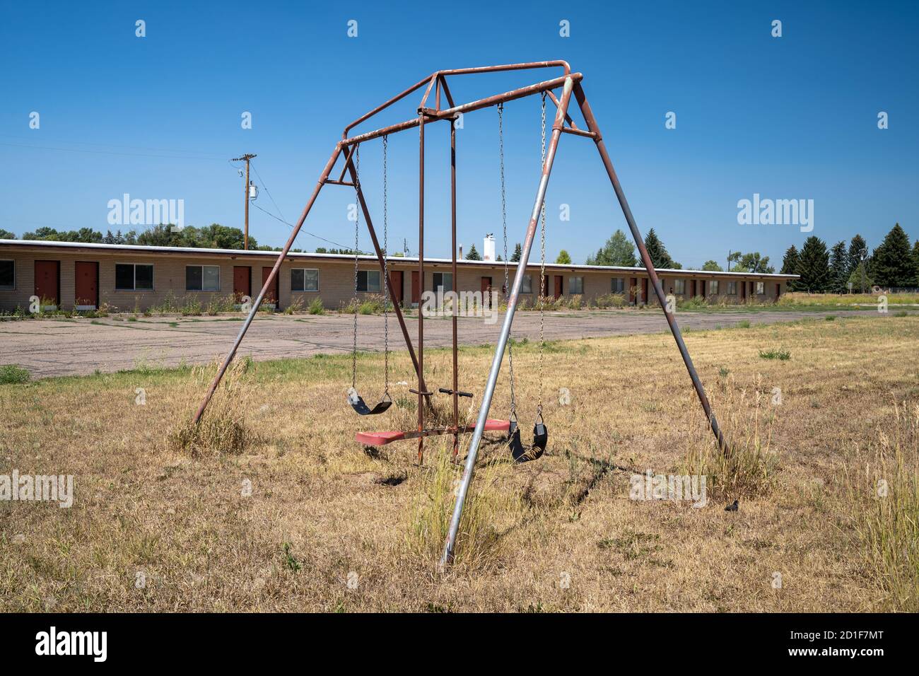 In un cortile si trova un'attrezzatura da gioco arrugginita con un set da cigno di un motel abbandonato Foto Stock