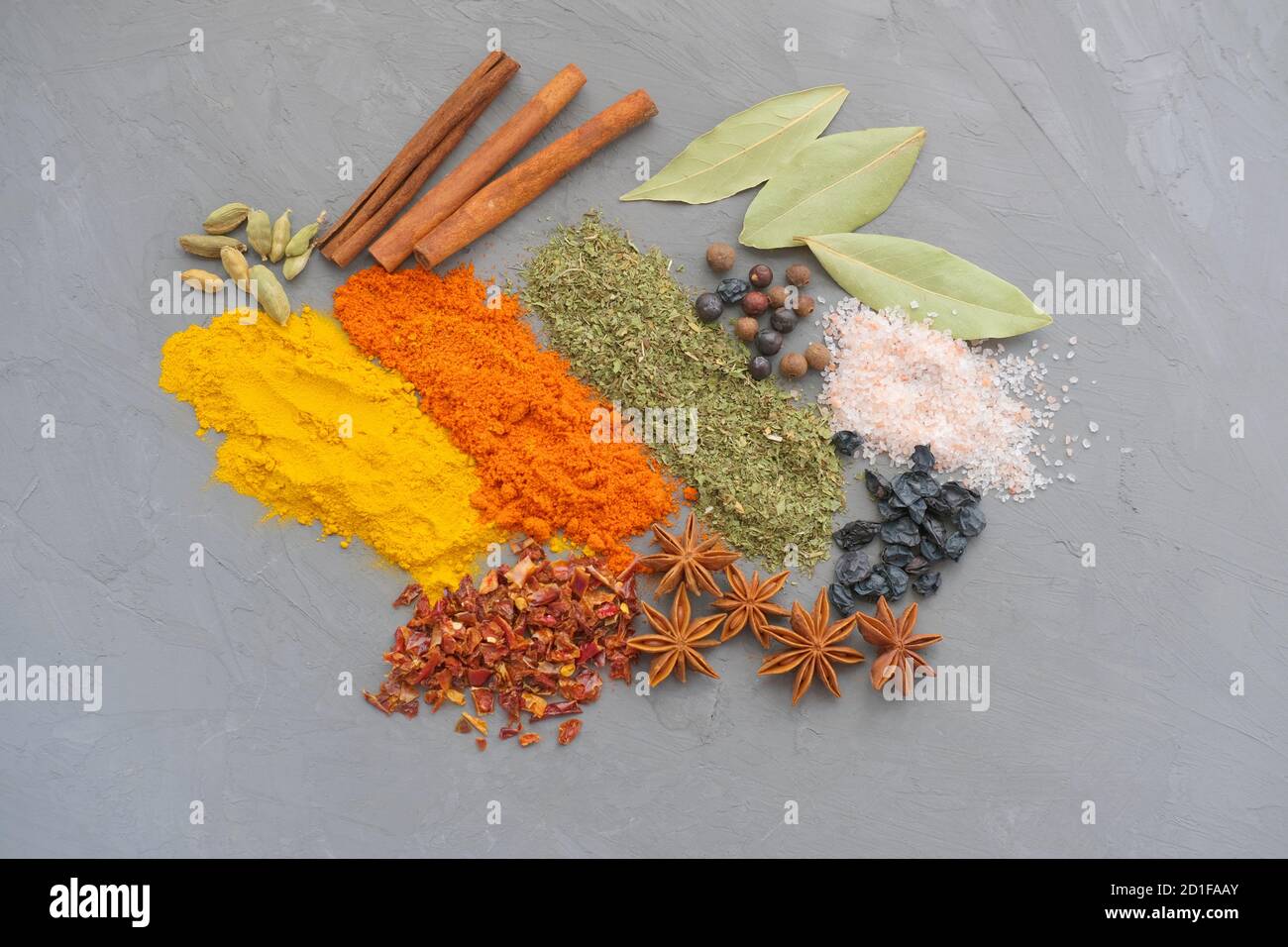 spezie su fondo grigio. composizione festosa composta da cannella, pepe, anice, sale turmerico e rosa. vista dall'alto. spezie asiatiche o condimento orientale. Foto Stock